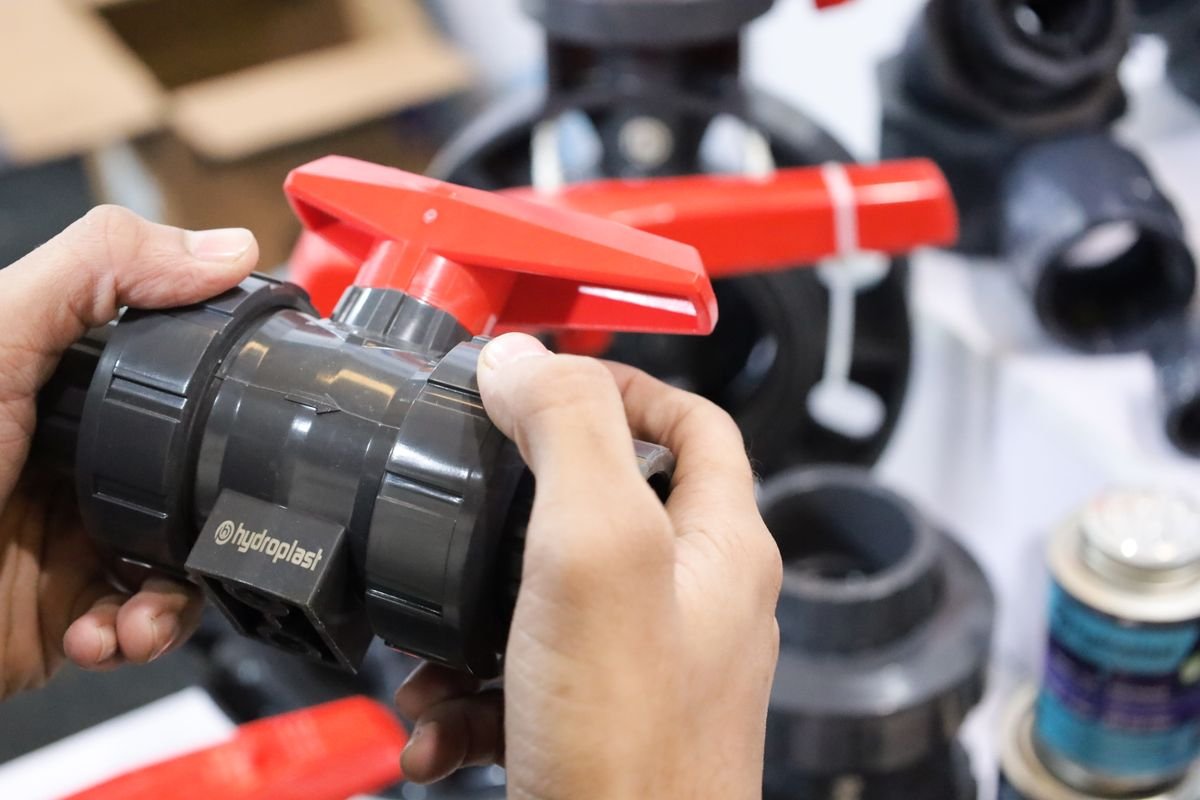 Plumber testing pipework and isolation valves under a kitchen sink in a bright London home