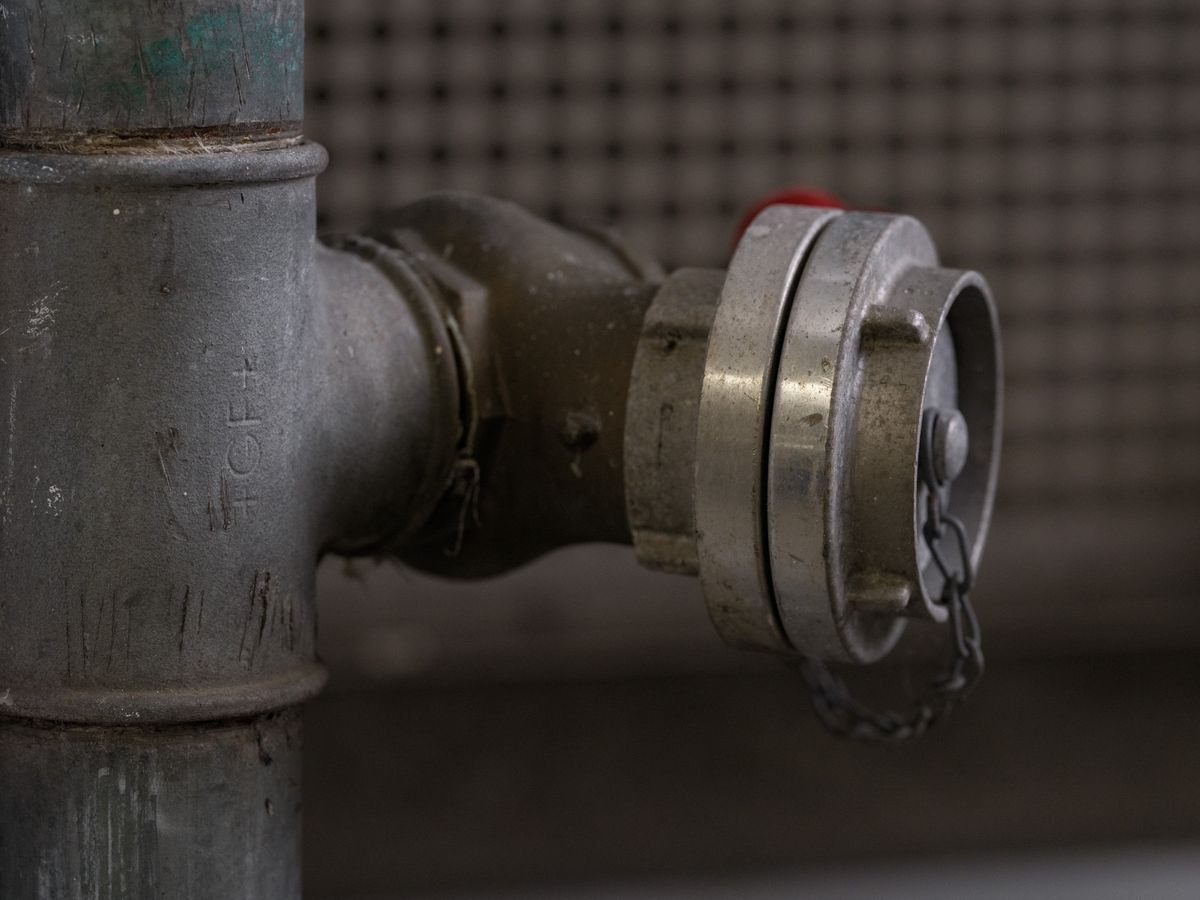 A burst copper pipe being isolated and repaired by a plumber